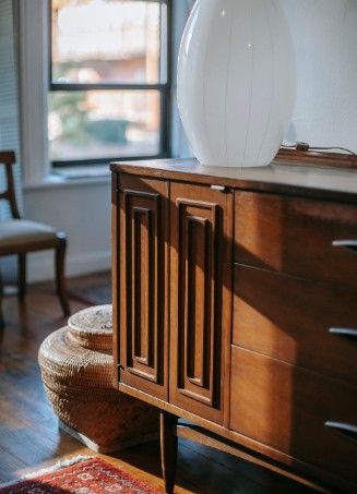 Aparador de madera oscura con puertas de cuarterones y lámpara de sobremesa