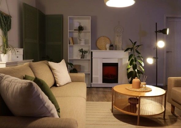 Salón con chimenea eléctrica en mueble blanco, estantería y mesa de centro redonda